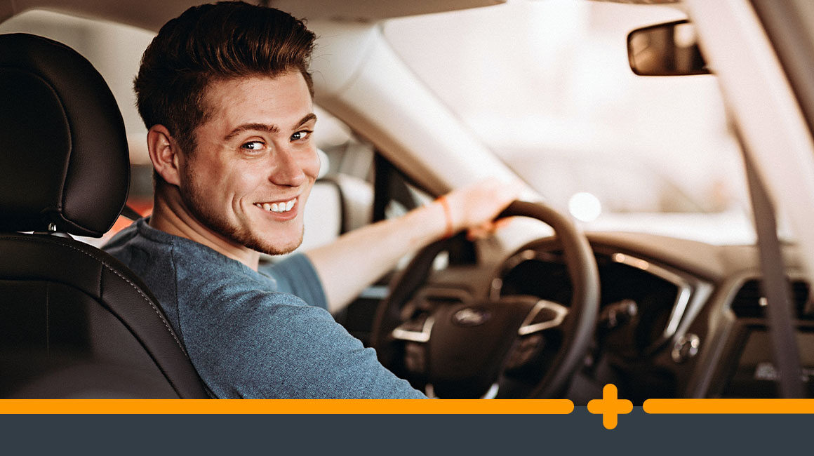 Młody mężczyzna w samochodzie, gotowy do jazdy, spoglądający przez ramię